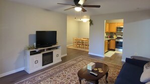 A living room with a TV, a ceiling fan, a dining area, and a kitchen. - Mid-Term Rental Furnished 2BR/2BA Condo in Germantown, MD (Germantown)