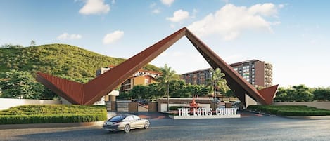 A modern building with a unique triangular entrance structure, a car in the foreground, and a sign reading 'THE LOTUS COUNTY'.