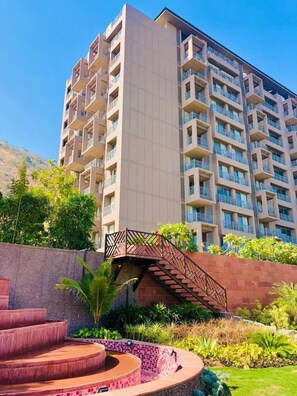 A multi-story hotel with balconies, a landscaped garden, and a staircase leading to the entrance. - The Lotus County Club Resort (Udaipur)
