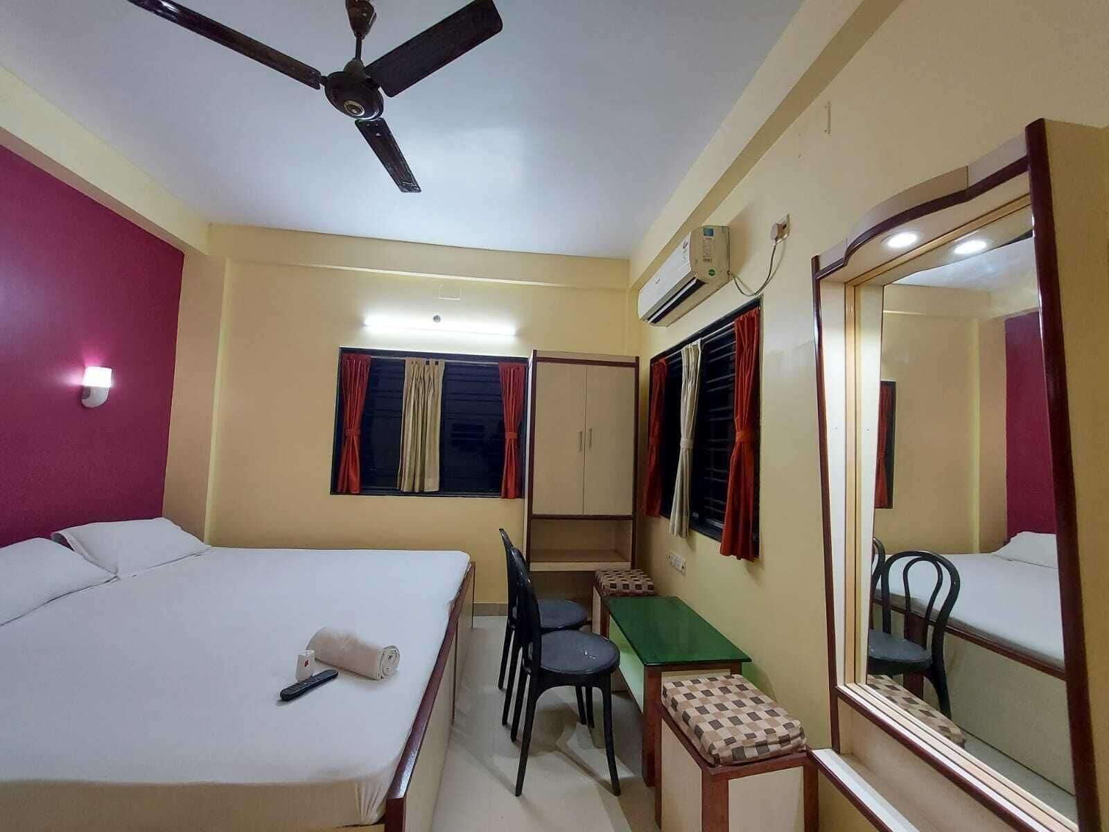 A hotel room with a bed, desk, chair, and a ceiling fan.