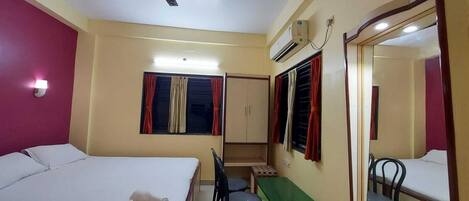 A hotel room with a bed, desk, chair, and a ceiling fan.