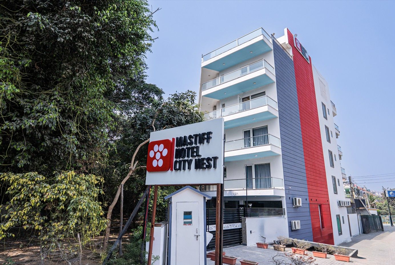 A multi-story building with a sign for 'Mastiff Hotel City West' featuring a logo with four circles.