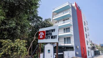 A multi-story building with a sign for 'Mastiff Hotel City West' featuring a logo with four circles.
