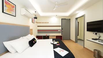 A hotel room with a bed, a desk, a TV, and a ceiling fan.