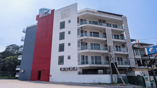 A multi-story building with a red and white facade, balconies, and air conditioning units. - Mastiff City Nest Golf Course Extension by Othpl (Gurugram)