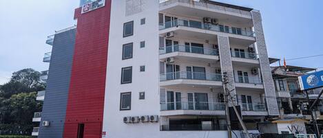 Un edificio a più piani con facciata rosso e bianco, balconi e condizionatori.