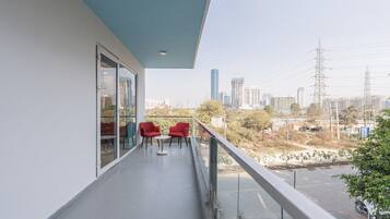 Ein Balkon mit Blick auf die Stadt, rote Stühle und eine Glastür zu einem Zimmer.