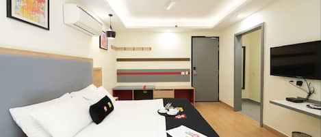 A hotel room with a bed, a desk, a TV, and a ceiling fan.