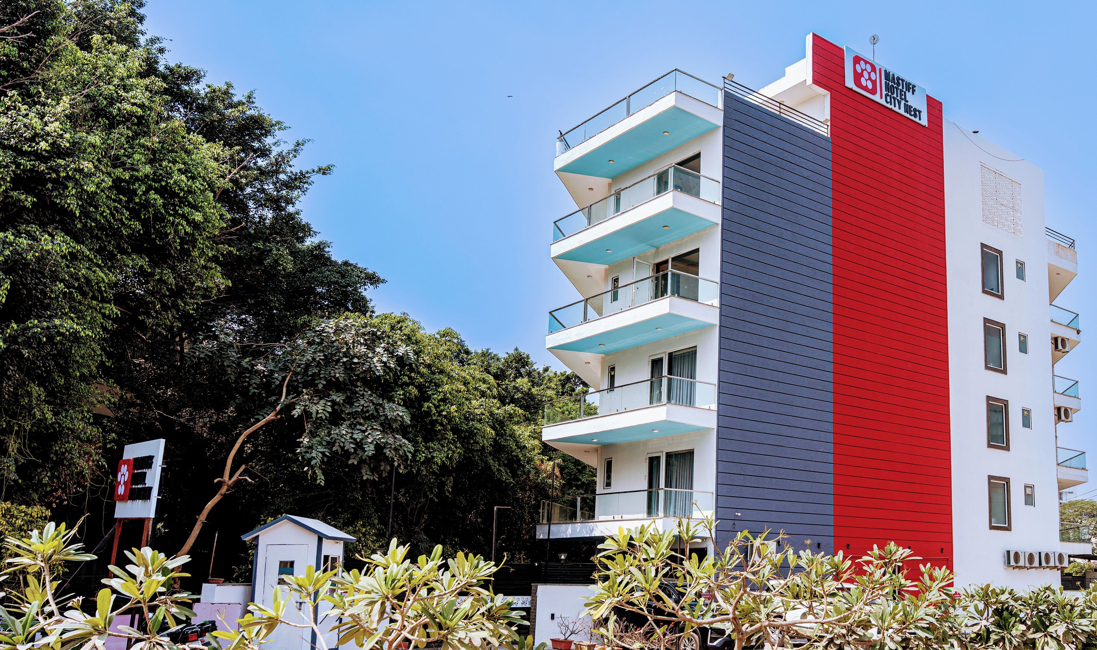 A multi-story hotel with a red and blue facade, balconies, and a sign indicating it's the Mastiiff Hotel City West.