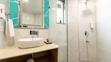 A bathroom with a large white sink, a glass shower enclosure, and a mirror with a teal accent wall.