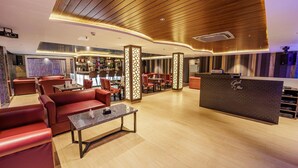 A modern lounge area with leather seating, a bar, and a reception desk. - Casa De Katson (Alto de Porvorim)
