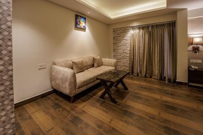 A living room with a sofa, a coffee table, a stone accent wall, and a curtain. - Casa De Katson (Alto de Porvorim)