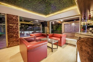 A modern interior with leather sofas, a glass table, and a bar area. - Casa De Katson (Alto de Porvorim)