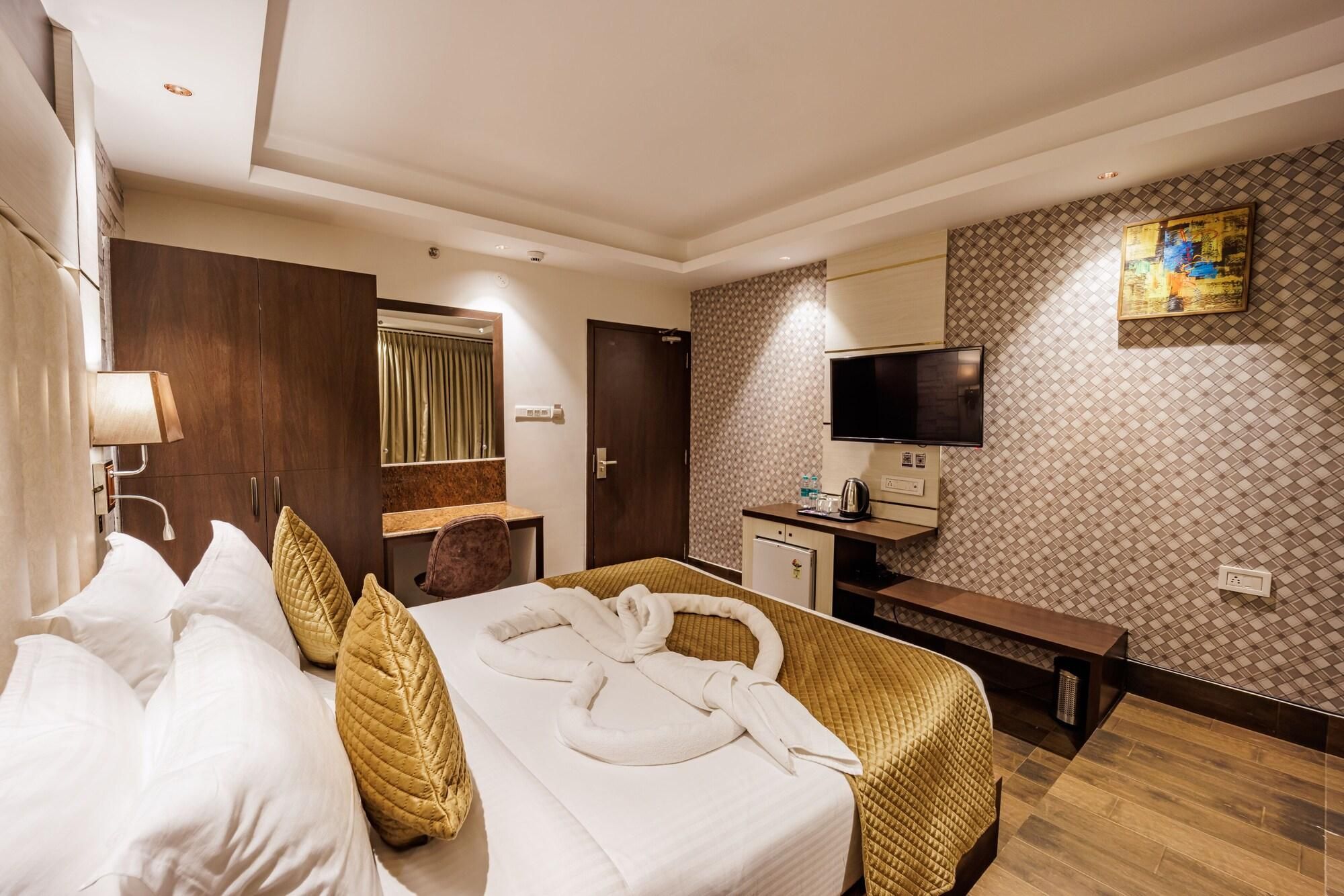 Une chambre d’hôtel équipée d’un lit, d’un bureau, d’une télévision et d’un mini-bar.