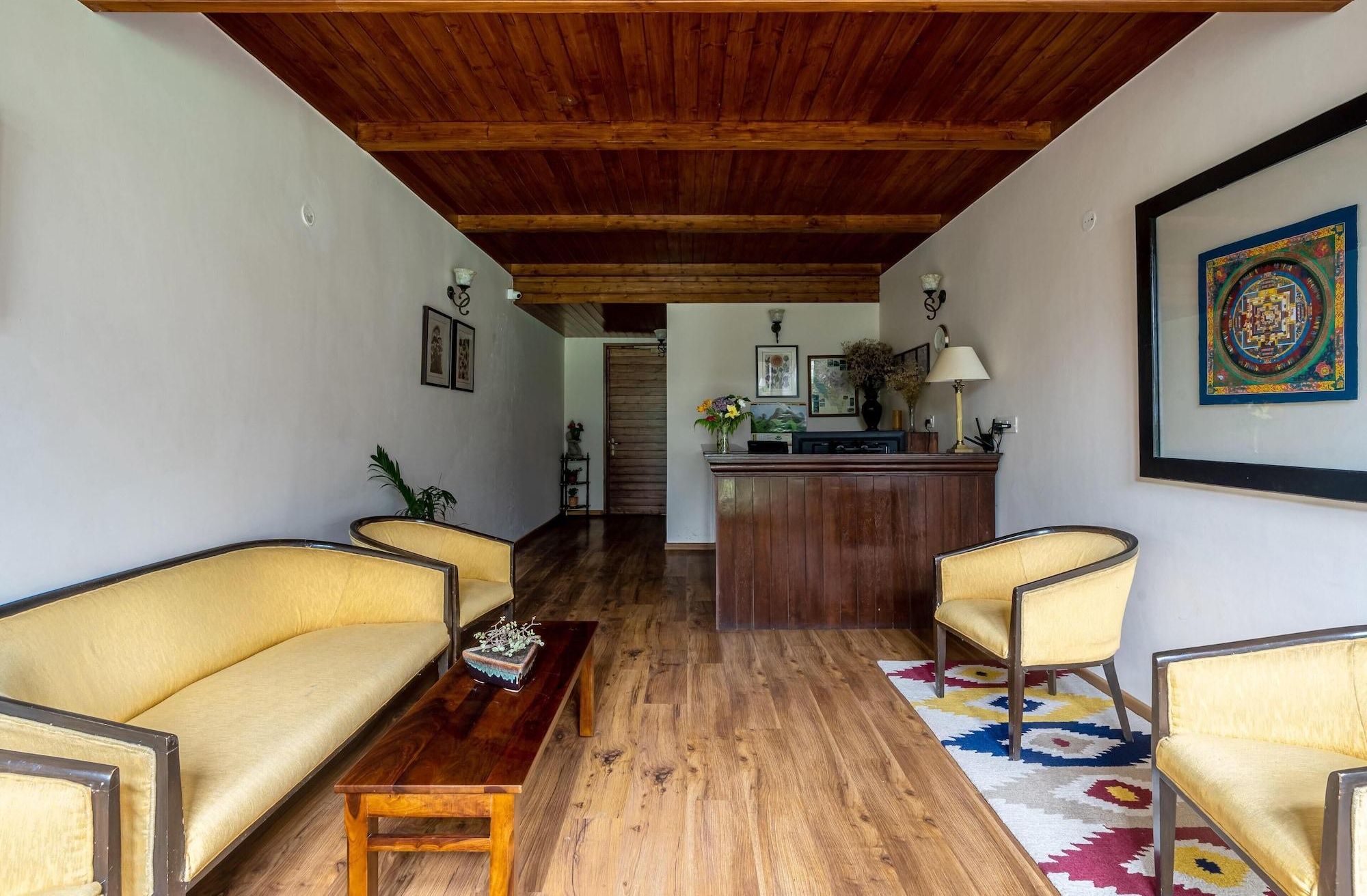 Una stanza con soffitto in legno, una scrivania della reception, un divano, un tavolino da caffè e un tappeto decorato.