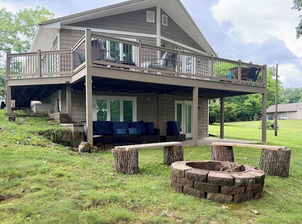 A two-story house with a balcony, a covered patio area, and a fire pit.