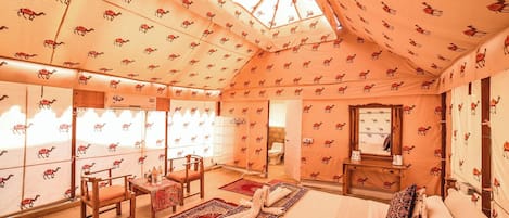 Une chambre décorée sur le thème des chameaux, avec un lit, des chaises, une table et un miroir.