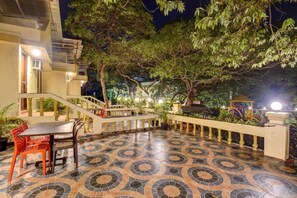 A courtyard with a tiled floor, a staircase, and a seating area with chairs. - Ishwar Inn Resort (Mahabaleshwar)