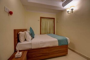 A single bed with a wooden frame, white bedding, and a teal throw.
