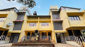 A yellow multi-story building with balconies, a satellite dish, and a water tank. - Ishwar Inn Resort (Mahabaleshwar)