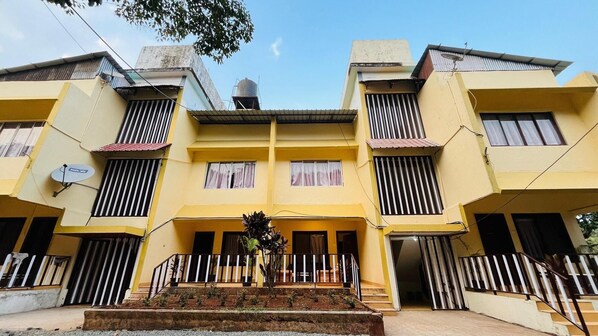 A yellow multi-story building with balconies, a satellite dish, and a water tank.