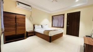 A bedroom with a bed, wardrobe, bedside table, and a window with curtains.