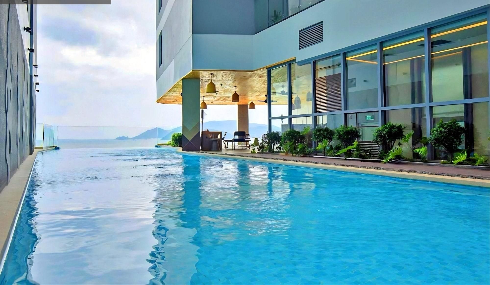 A swimming pool with a view of the sea, a modern building with large windows, and outdoor seating.
