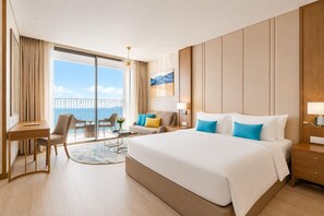 Une chambre d’hôtel avec un grand lit, un bureau, une chaise, un canapé et une vue sur l’océan.