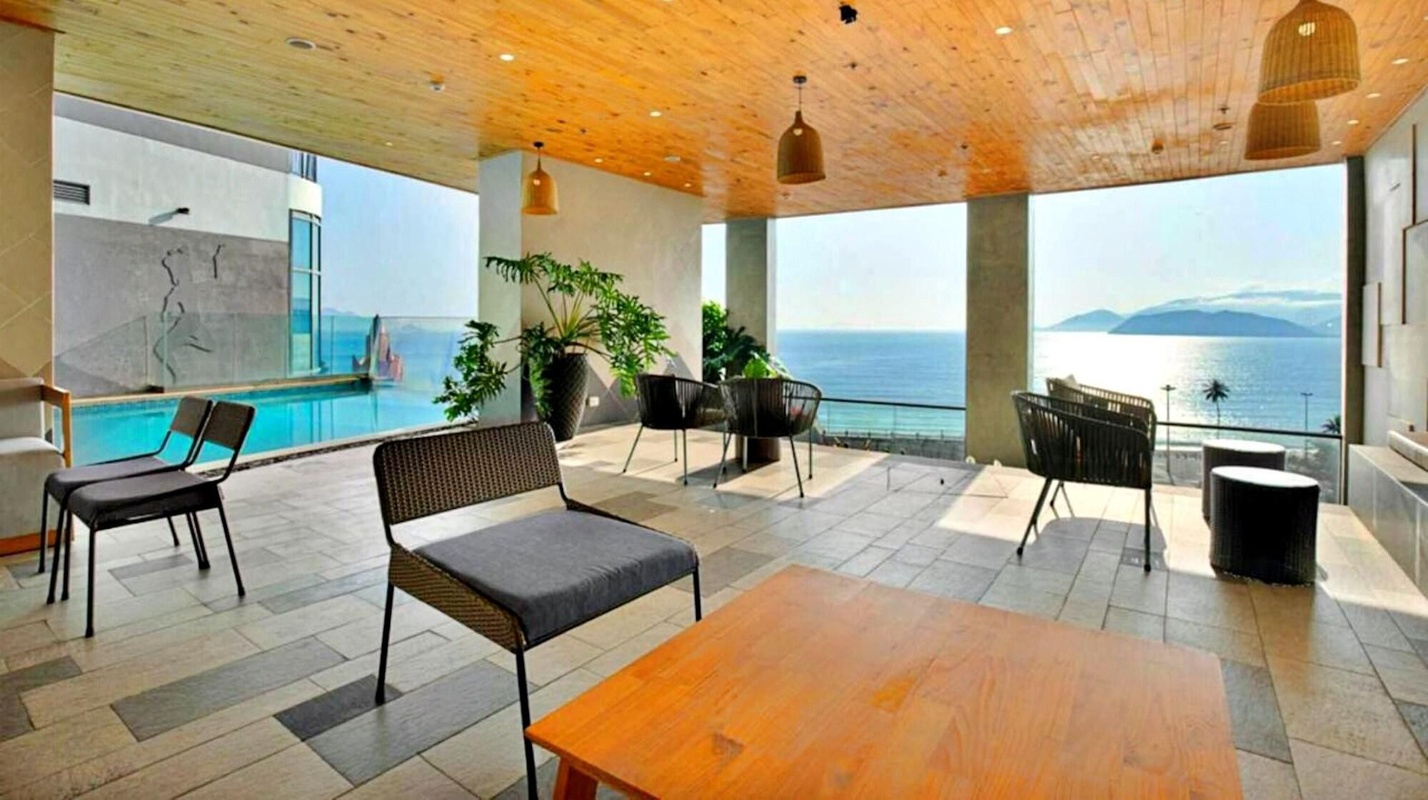Un área lounge moderna con piscina, asientos y vistas al mar.