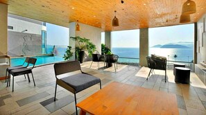 Un espace de détente moderne avec une piscine, des sièges et une vue sur la mer.