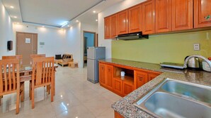 A modern kitchen with wooden cabinets, a granite countertop, and a stainless steel sink. - Hanz Business Suite Oceanus Condotel (Bac Nha Trang)