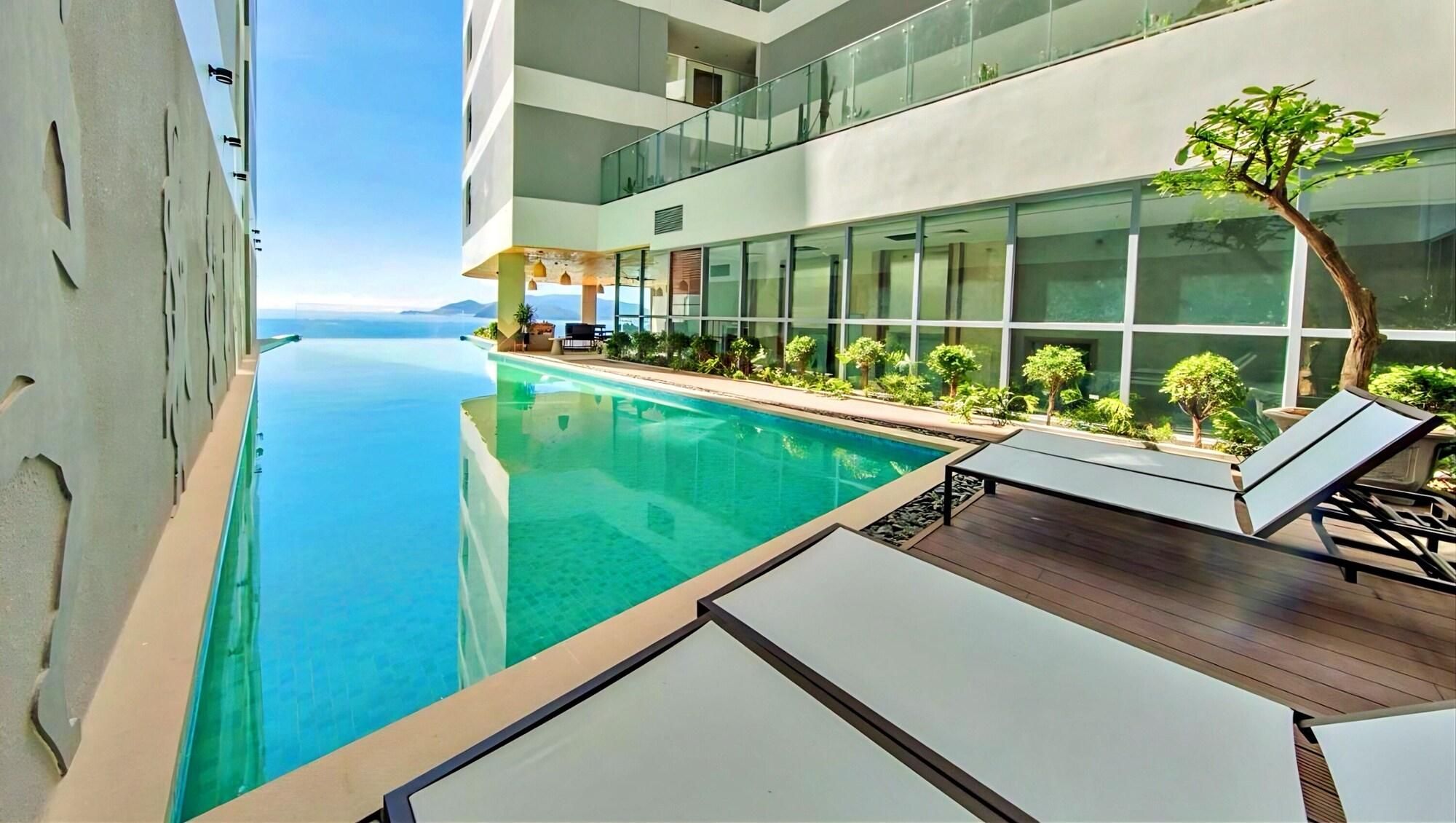 Un hotel moderno con piscina, sillones de descanso y vista al mar.
