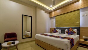 Ein Hotelzimmer mit Bett, Stuhl, kleinem Tisch und Spiegel.