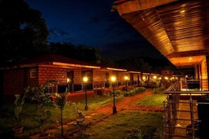 A brick building with a covered outdoor area, a pathway, and potted plants. - The Redstone Resort (Alibag)