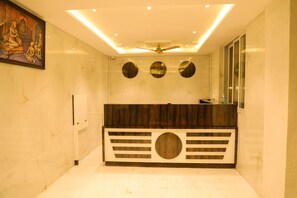 A bathroom with a marble floor, a wooden vanity with a circular design, a ceiling fan, and a wall-mounted mirror. - The Redstone Resort (Alibag)