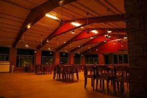 An indoor space with a high ceiling, exposed beams, and multiple tables and chairs arranged for dining. - The Redstone Resort (Alibag)