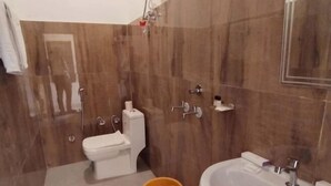 A bathroom with a toilet, sink, mirror, and a hairdryer mounted on the wall. - Skyza Rooftop Lodge (Jaipur)