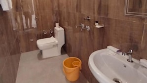 Une salle de bain équipée de toilettes, d’un lavabo, d’un miroir et d’un sèche-cheveux fixé au mur.