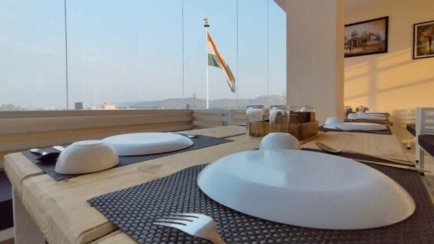 Un coin repas avec une table dressée pour deux personnes, une vue sur le ciel et un drapeau à l’ext érieur.