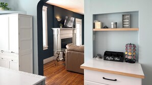 A modern kitchen with a white countertop, a coffee bar, and a fireplace.