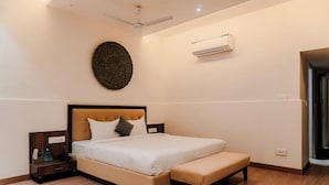 A bedroom with a bed, bedside table, and an air conditioning unit. - Kumbhalgarh Valley Resort Kumbhalgarh (Kumbhalgarh)