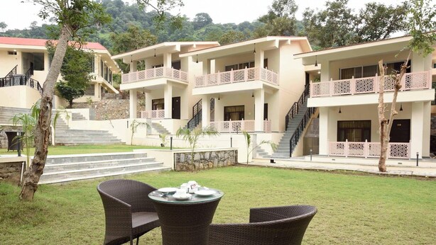 A courtyard with wicker furniture, a staircase, and a building with balconies. - Kumbhalgarh Valley Resort Kumbhalgarh (Kumbhalgarh)