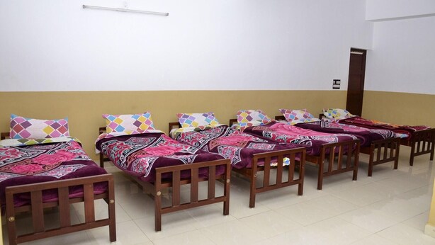 Un dormitorio con varias camas, cabeceros de madera y piso de baldosas.