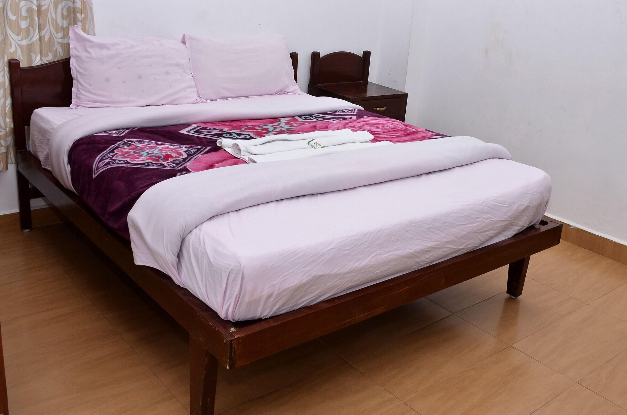 A bed with a wooden frame, a white mattress, and a patterned blanket.