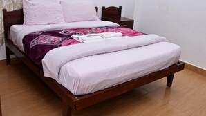 A bed with a wooden frame, a white mattress, and a patterned blanket.