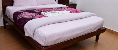 A bed with a wooden frame, a white mattress, and a patterned blanket.