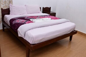 A bed with a wooden frame, a white mattress, and a patterned blanket.