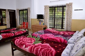 A room with two beds, a small table, and a window with curtains. - Ac Mist (Kanayannur)