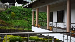 A building with a balcony, columns, and potted plants.