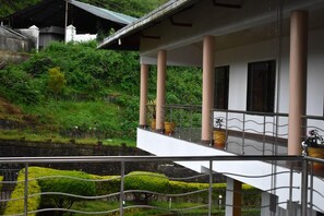 A building with a balcony, columns, and potted plants.